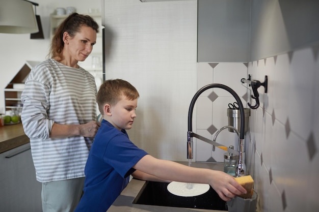 Little boy helping mother in kitchen
