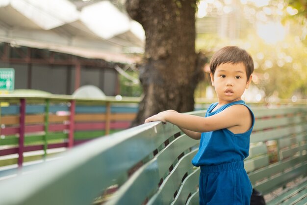 Little boy hold on green wooden fence