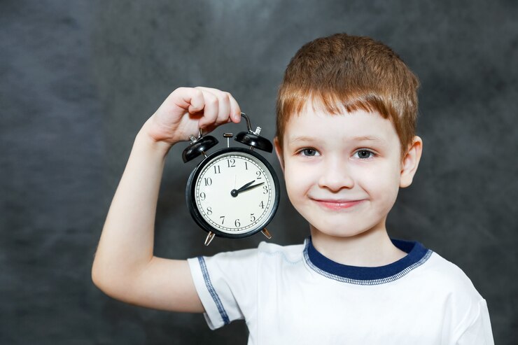 Little boy holding alarm clock.