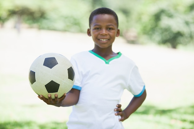 カメラで笑いながら公園でサッカーをしている少年