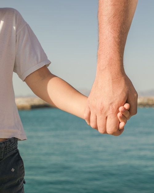 Little boy holding the hand of his father