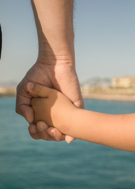 Little boy holding the hand of his father