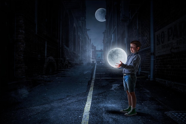 Little boy holding moon at night. Mixed media