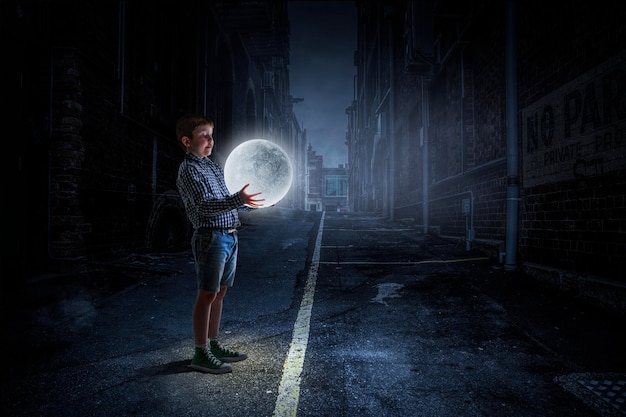 Little boy holding moon at night. Mixed media