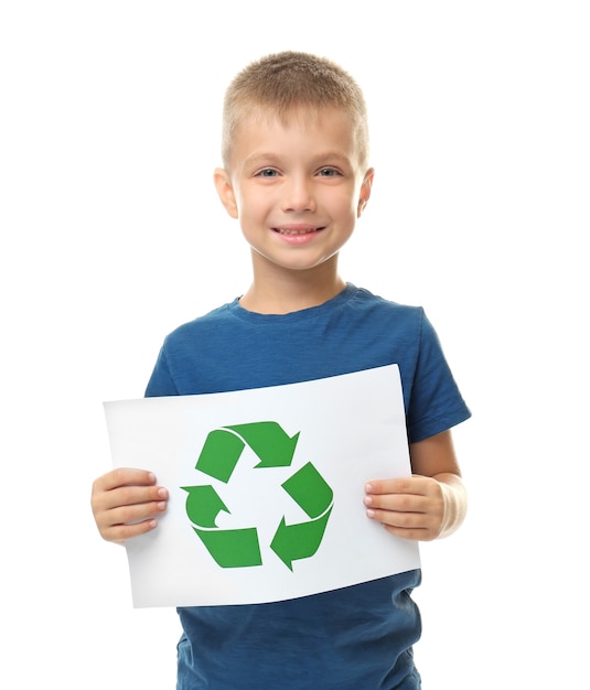 Little boy holding paper sheet with recycling symbol on white background