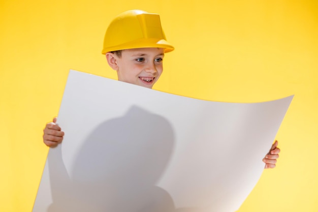A little boy holding plan project in his hands dreams of becoming a famous architect