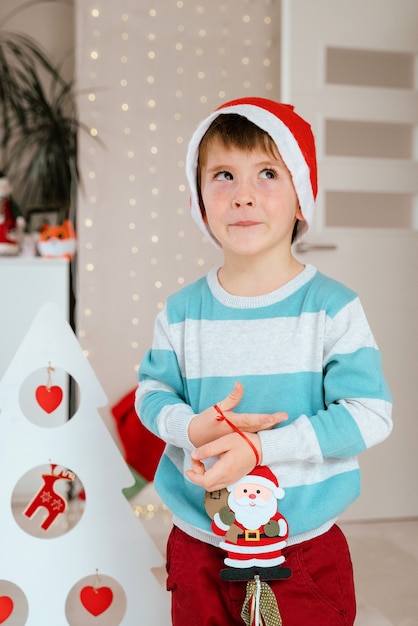 Little boy holding a Santa Claus ornament for Christmas decoration