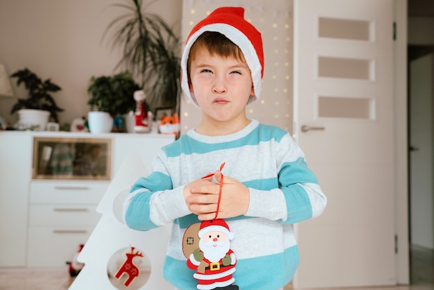 Little boy holding a Santa Claus ornament for Christmas decoration