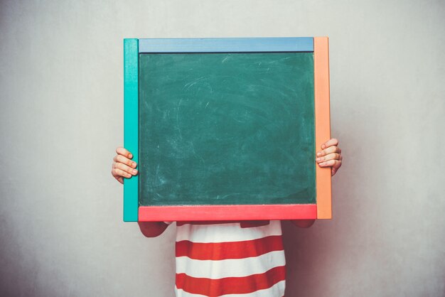 Ragazzino che tiene la bandiera del bordo verde della scuola davanti alla sua testa