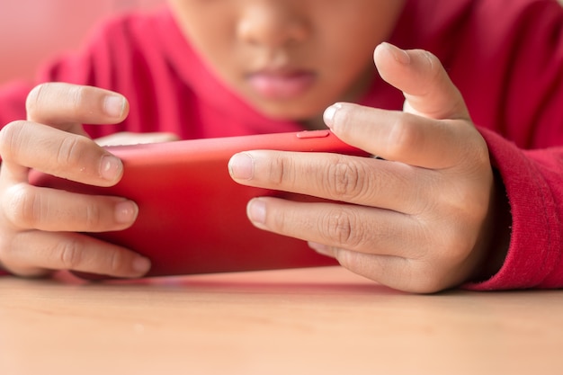 Little boy holding smartphone in horizontal position 