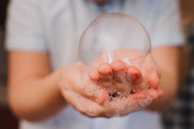 Foto bolla di sapone della tenuta del ragazzino in sua mano