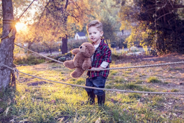 A little boy holding a teddy bear in a field.