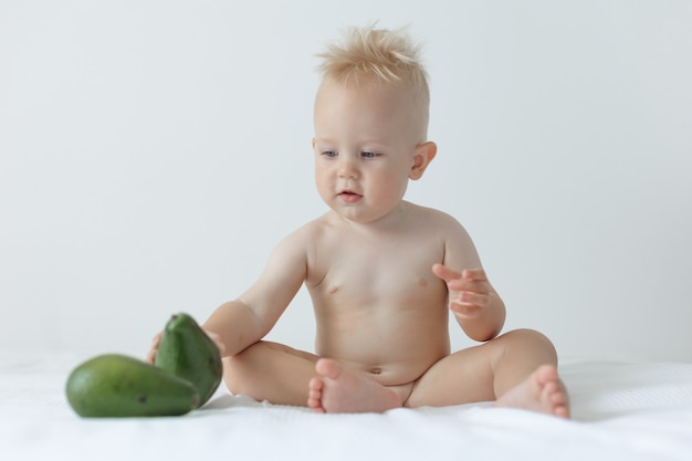 Фото Маленький мальчик держит в руках авокадо и улыбается