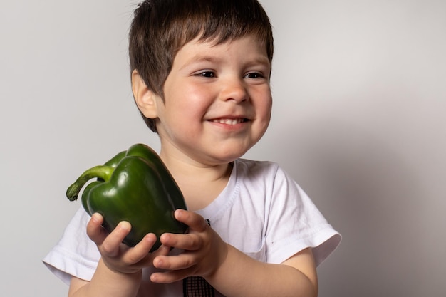 Little boy holds green pepper in his hands