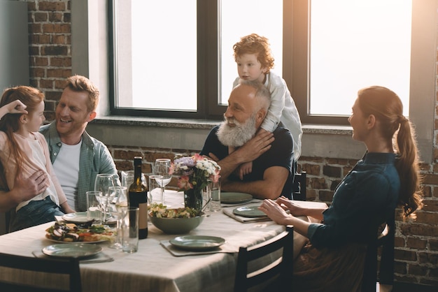 little boy hugging grandfather during family dinner at home