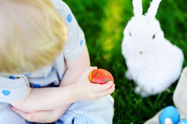 Little boy hunting for easter egg in spring garden on Easter day. Cute little child with traditional bunny celebrating feast