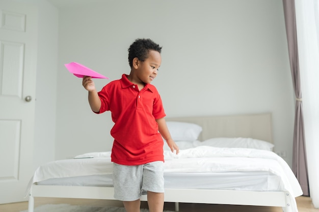 A little boy imagines being a pilot playing with toy planes at\
home