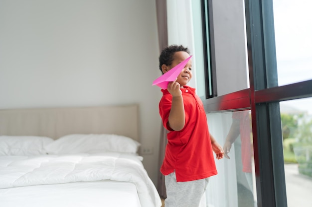 A little boy imagines being a pilot playing with toy planes at\
home