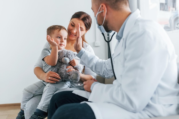 Il bambino è in visita due medici in camice bianco sono in clinica che lavorano insieme