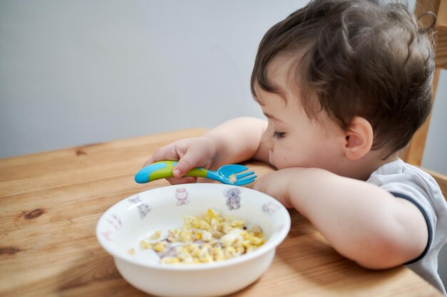 Little boy is eating eggs for breakfast and fooling around making faces person