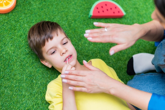 A little boy is engaged in a speech therapist's office and corrects his speech while lying on the floor