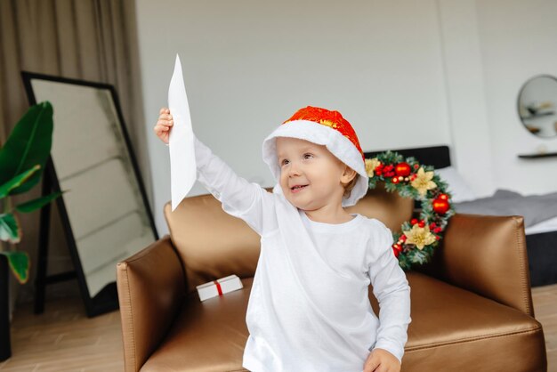 The little boy is holding a letter to santa claus christmas mood to make a wish