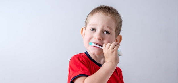 A little boy is learning to brush his teeth using a toothbrush