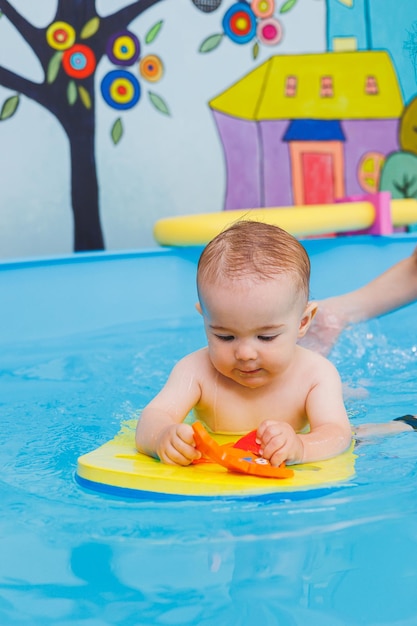 A little boy is learning to swim in a baby pool Children's development First swimming lessons for children