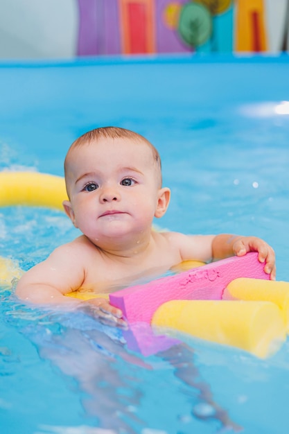 小さな男の子がベビープールで泳ぐことを学んでいます 子供の発達 子供のための最初の水泳レッスン