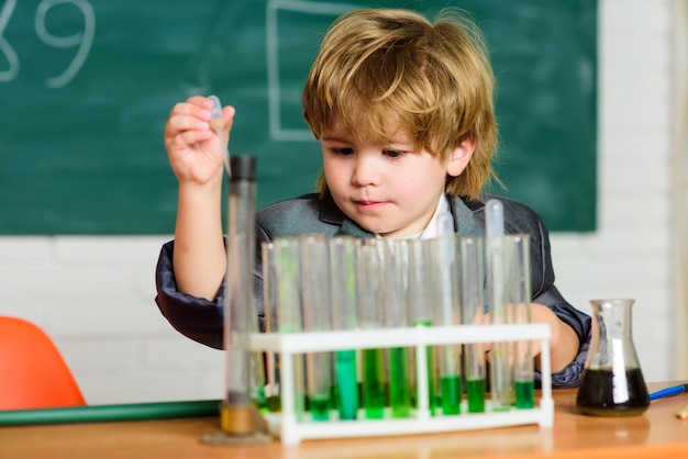 Little boy is making science experiments school kid scientist studying science biology science experiments in lab little boy at lesson Back to school Looking at the future of science