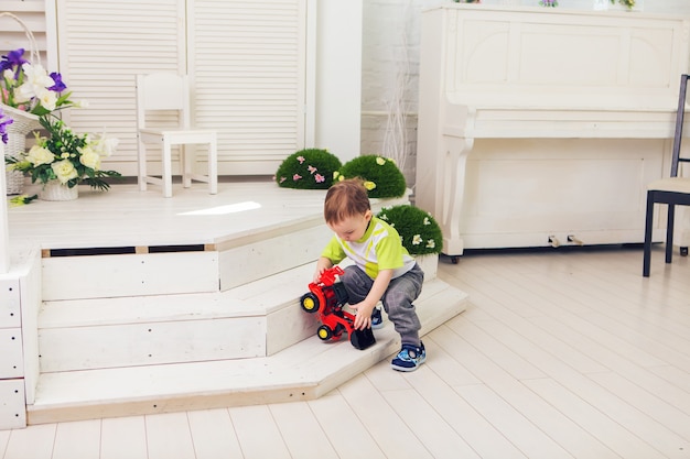 Маленький мальчик играет с игрушечной машинкой дома.