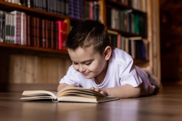little boy is reading a book in the library at home