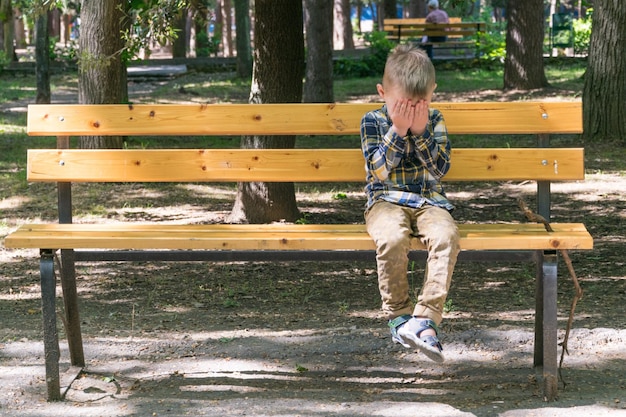 小さな男の子がベンチで休んでいます