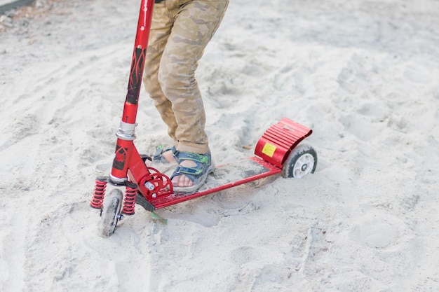 A little boy is riding a scooter on the sand Irresistible obstacle for the child