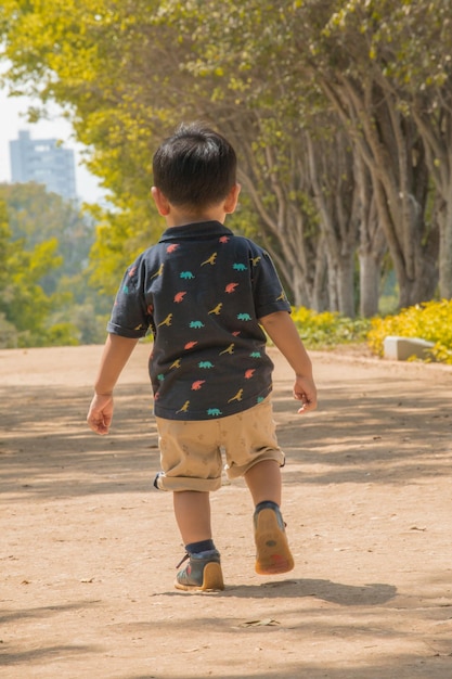 a little boy is running on a dirt road with a shirt with the word parrot on it