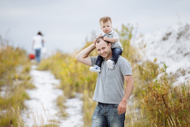 Little boy is sitting on fathers shoulders and playing in the park