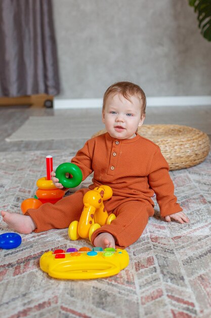 小さな男の子が家の床でおもちゃで遊んで座っています