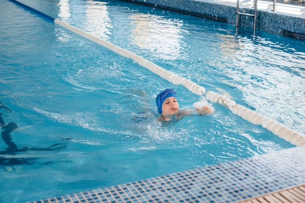 어린 소년이 수영장에서 수영하고 웃고 있습니다. 건강한 생활.