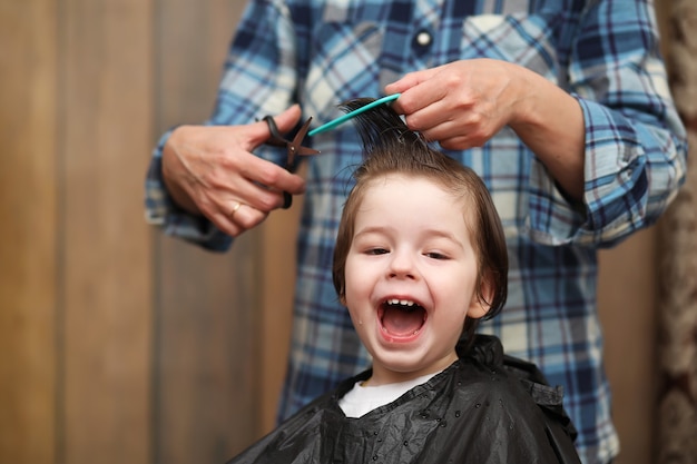 Photo a little boy is trimmed in the hairdresser's bright emotions on his face