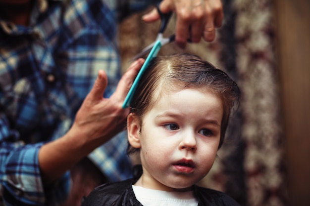 Photo a little boy is trimmed in the hairdresser's bright emotions on his face