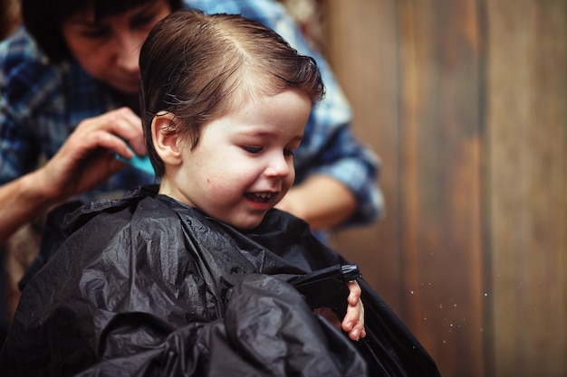 Маленький мальчик подстрижен в ярких эмоциях парикмахера на лице