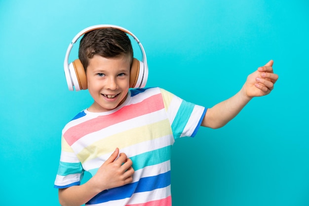 Little boy isolated on blue background listening music and doing guitar gesture