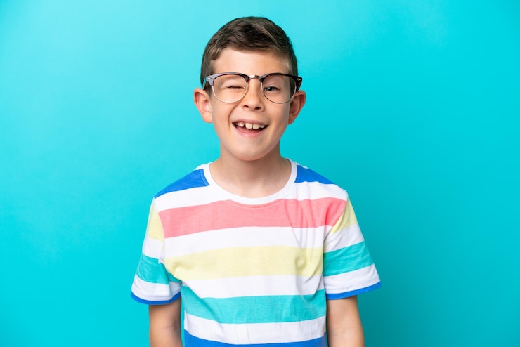 Photo メガネと幸せそうな表情で青い背景に分離された小さな男の子