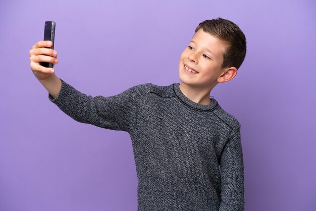 Little boy isolated on purple background making a selfie