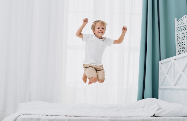 Photo little boy jumping while looking at the camera