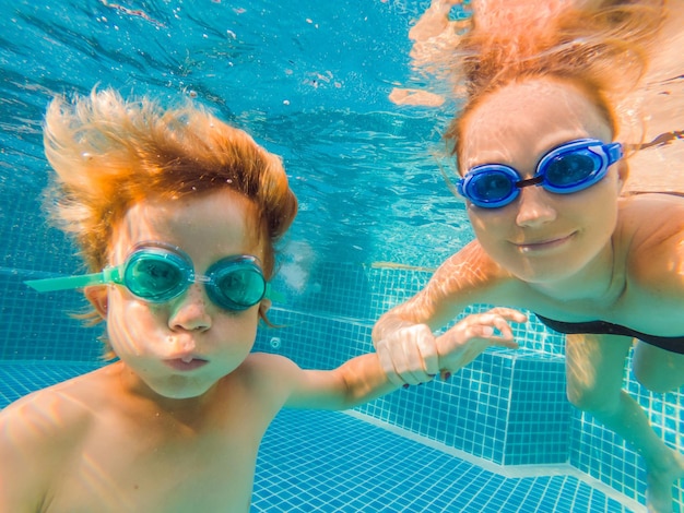 Little boy learning to swim in a swimming pool mother holding the child