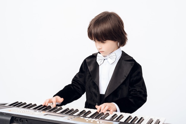 Photo the little boy learns the game on the synthesizer.