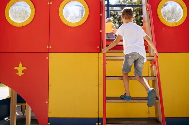 小さな男の子は遊び場でのんびり、幸せな子供時代。子供はトランポリンで遊ぶ