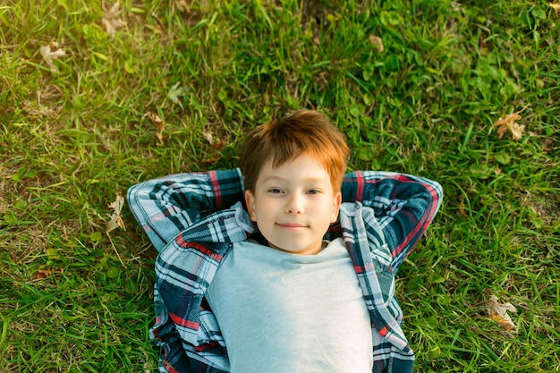 little boy lies on green grass