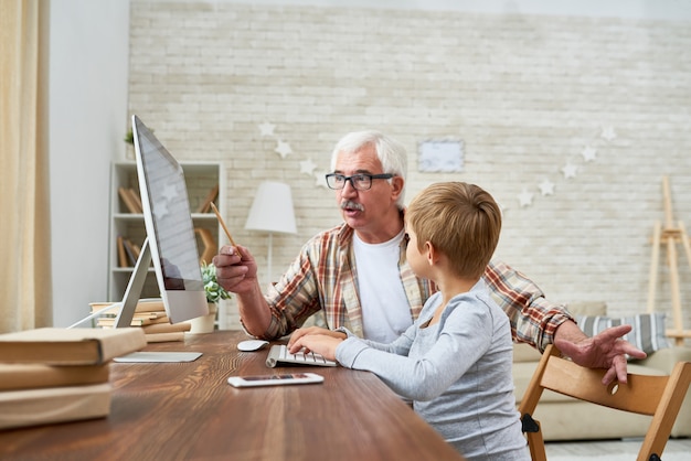 Little Boy Listening to Grandpa at Computer Desk